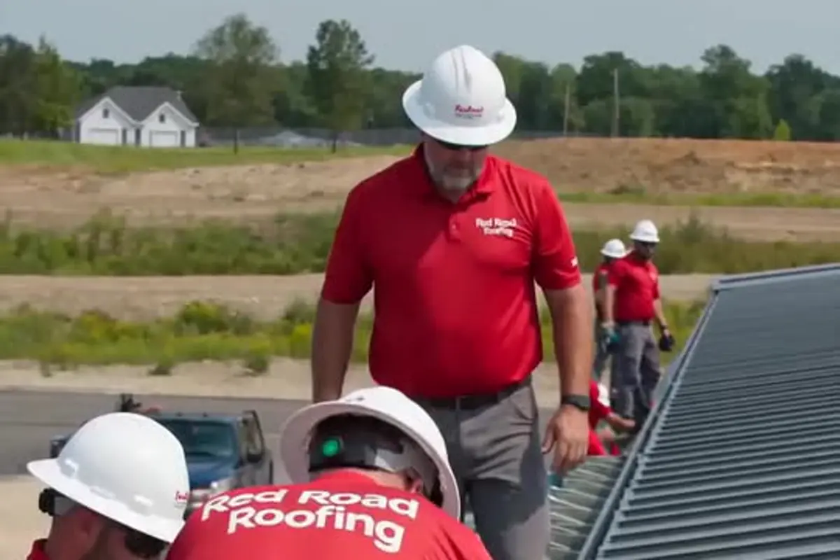 Roofing craftsmen in Red Road Roofing shirts working on a roof